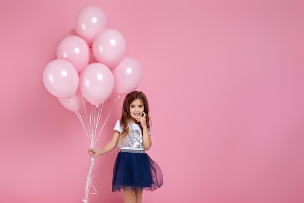 Niño niña posando con globos de aire rosa pastel