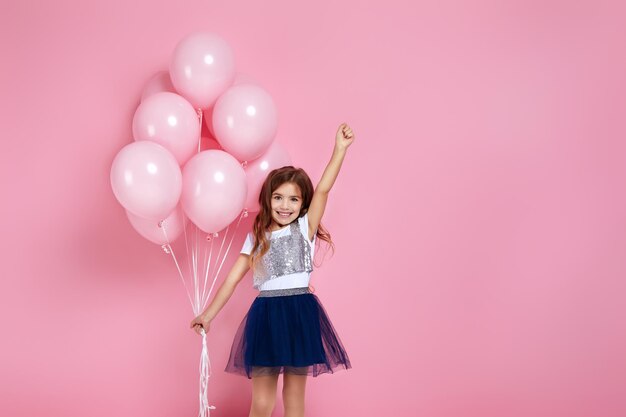 Niño niña posando con globos de aire rosa pastel