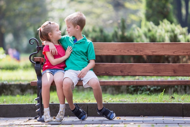 niño y niña sentada en un banco en el parque