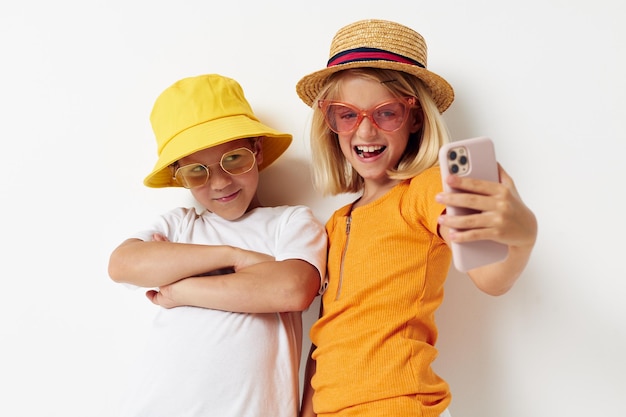 Niño y niña con sombreros con moda de teléfono posando infancia