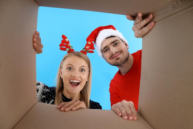 Un niño y una niña con sombreros de Navidad miran dentro de la caja