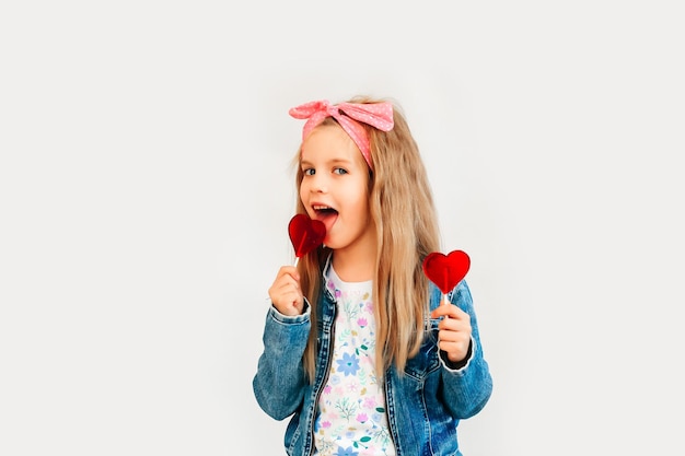 Niño, niña sosteniendo dulces en forma de corazón, aislado sobre fondo blanco.