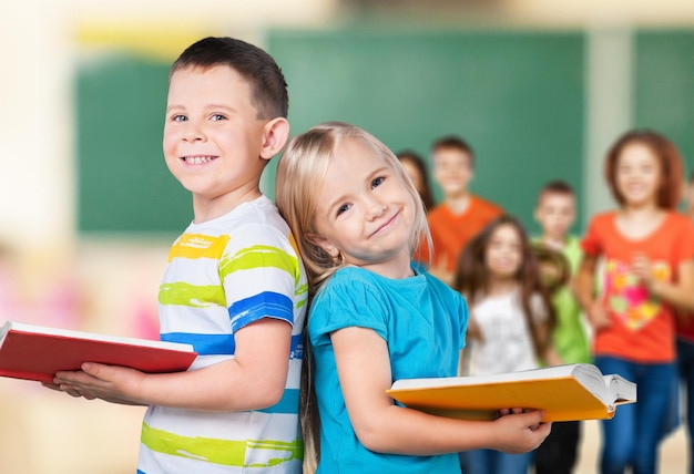 Niño y niña sosteniendo libros en la escuela