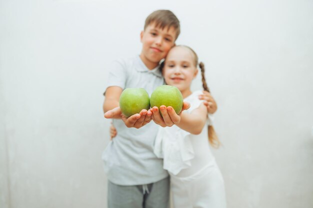 Un niño y una niña sostienen una manzana verde sobre un fondo blanco, el concepto es la salud de los dientes de los niños