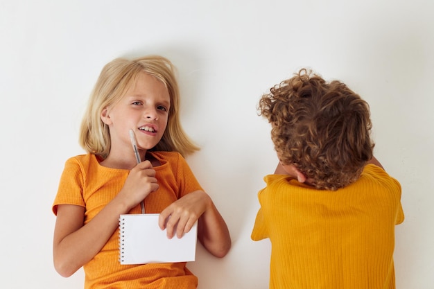 Niño y niña en el suelo con blocs de notas y lápices fondo aislado inalterado