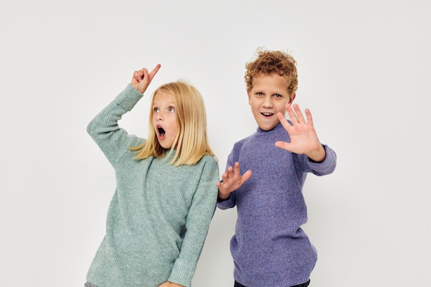 Niño y niña en suéteres multicolores posando para un estilo de vida divertido inalterado