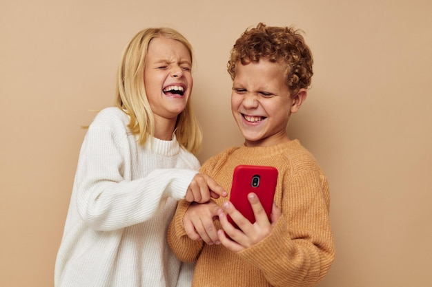 Niño y niña con un teléfono rojo juntos tecnologías fondo aislado