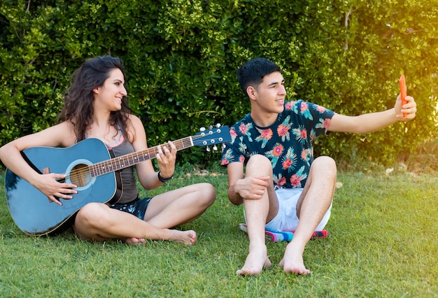 Niño y niña tocan la guitarra y cantan en el parque al aire libre en verano