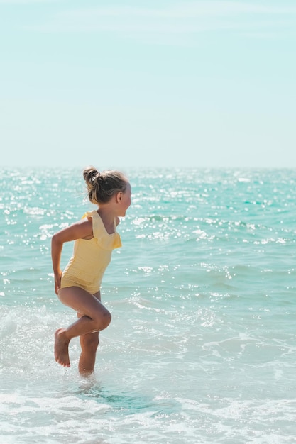 Niño niña en traje de baño amarillo en el mar