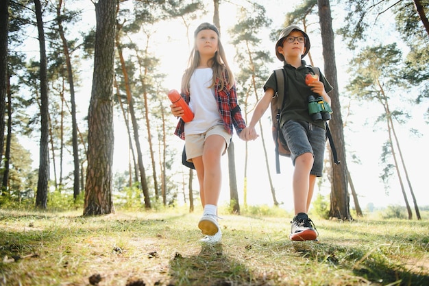 Niño y niña van de excursión por un camino forestal