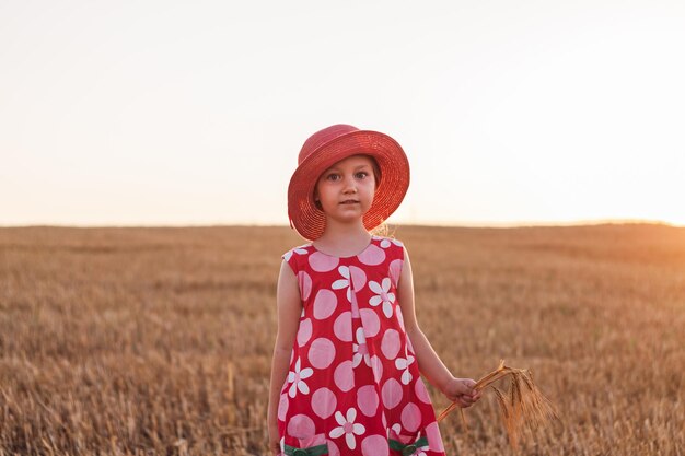 Niño niña en vestido de sombrero de paja en campo de trigo Niño sonriente en gafas de sol puesta de sol campo Estética de estilo Cottagecore