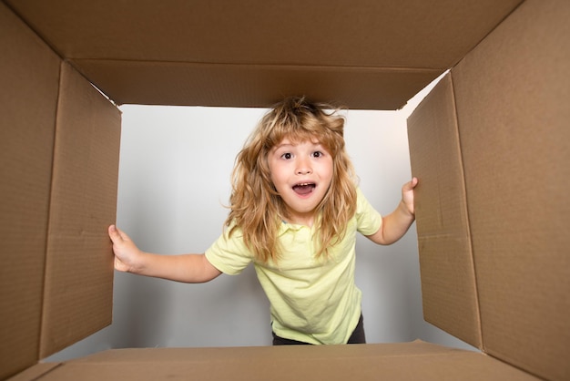 Niño niño abriendo una caja de cartón y mirando dentro del concepto de desembalaje sorpresa unboxing Concepto de embalaje o desembalaje de paquetes