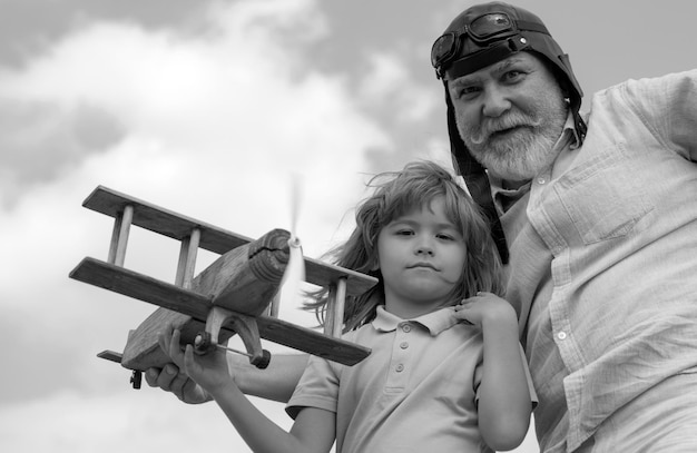 Niño niño y abuelo jugando con avión de madera contra el fondo del cielo de verano niño niño con dre