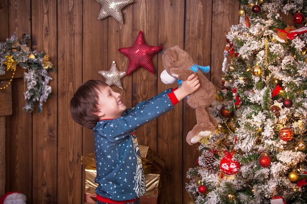 Niño niño en el árbol de Navidad con regalos