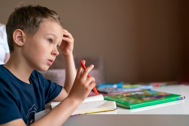 Foto niño niño con cabello oscuro estudia en casa niño haciendo la tarea