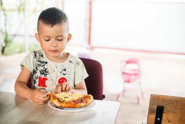 Un niño, un niño en la calle se come una mini pizza muy apetecible