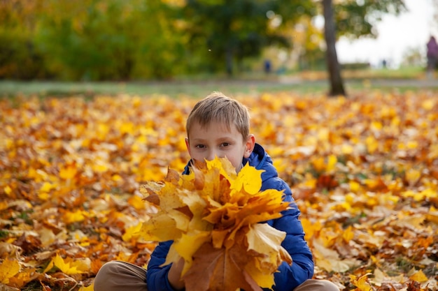 Niño niño caminando en el parque de otoño Concepto de niños de hojas de otoño