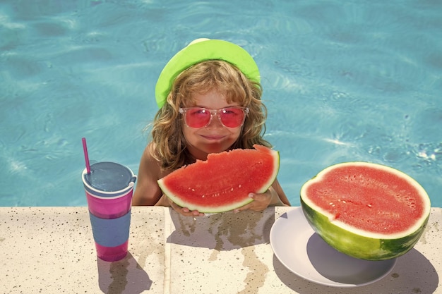 Niño niño come sandía en la piscina Concepto de vacaciones de verano Retrato de niños de verano con sandía en el agua de la piscina