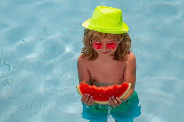 Niño niño come sandía en la piscina Concepto de vacaciones de verano Retrato de niños de verano con sandía en el agua de la piscina