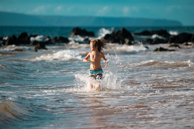 Niño niño en la costa niño jugando en el océano vacaciones en el mar el niño en olas