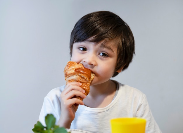 Niño niño crujiente para su desayuno antes de ir a la escuela por la mañana, comida saludable para el concepto de niño