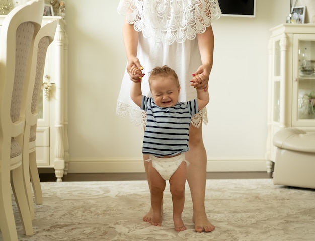 Foto niño niño feliz aprendiendo a caminar con ayuda de la madre en casa primeros pasos