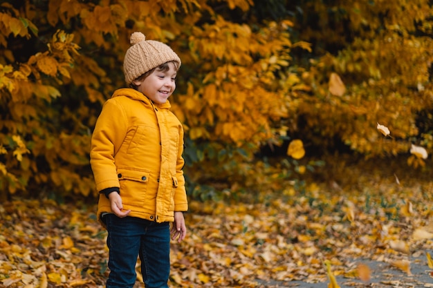 Niño niño feliz riendo y jugando en el día de otoño.