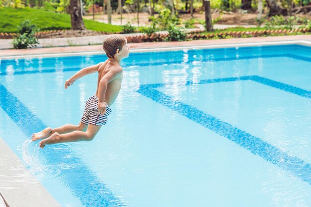 Niño niño feliz saltando en la piscina