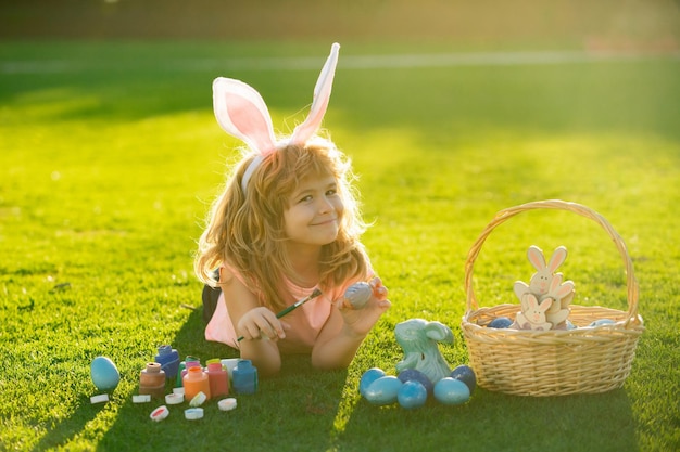 Niño niño con huevos de pascua y orejas de conejo al aire libre niño divertido conejito de pascua niños