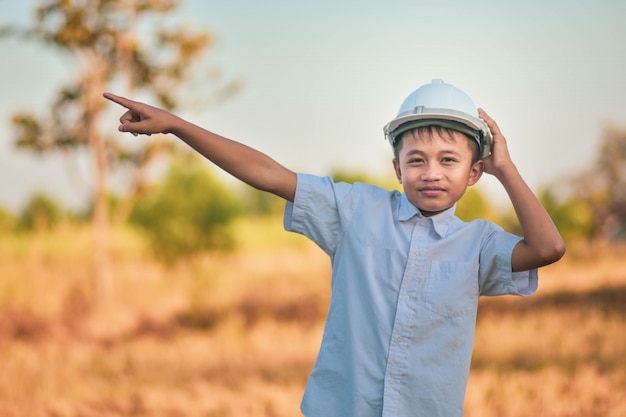 Niño niño ingeniero permanente al aire libre sosteniendo el concepto de éxito