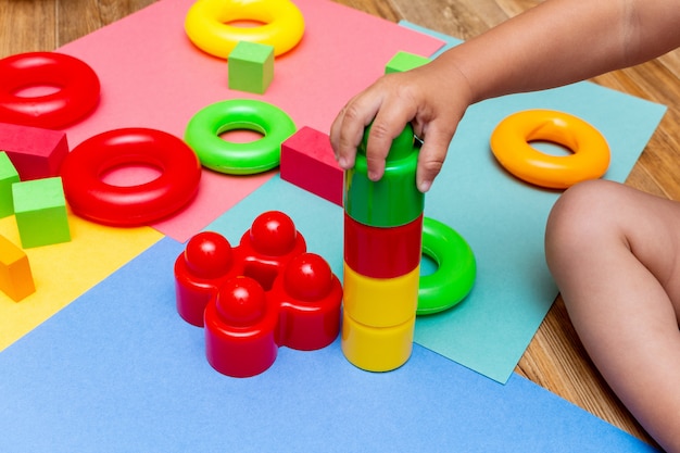 Niño niño jugando coloridos juguetes de educación en el fondo brillante. Concepto de bebés niños de la infancia.