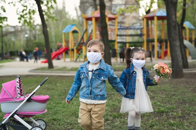 Niño niño y niña caminando al aire libre con protección de mascarilla. Coronavirus (COVID-19