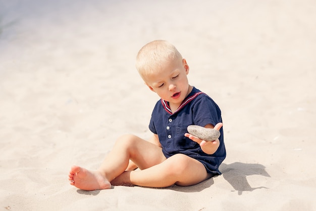 Niño niño niño jugando en piedra de arena de playa de mar