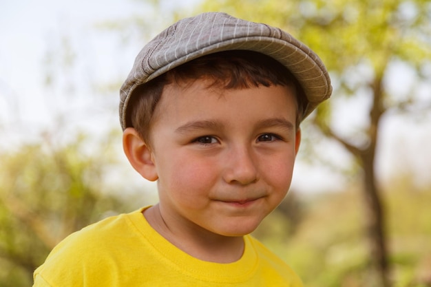 Niño niño pequeño retrato al aire libre con una cara de gorra al aire libre fuera de primavera