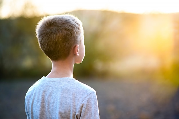 Niño niño de pie al aire libre en un día soleado de verano disfrutando de un clima cálido afuera