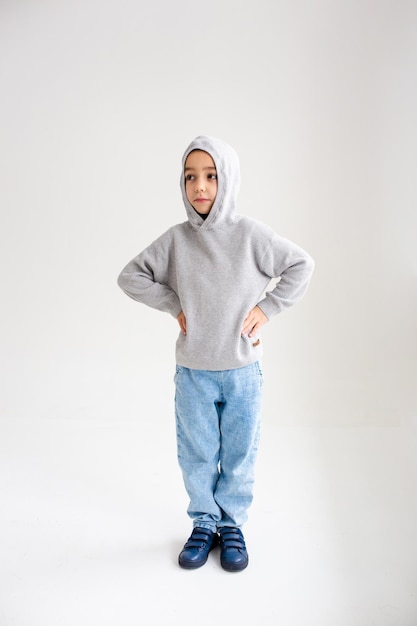 Niño niño preescolar sonriendo y posando sobre fondo gris en estudio fotográfico