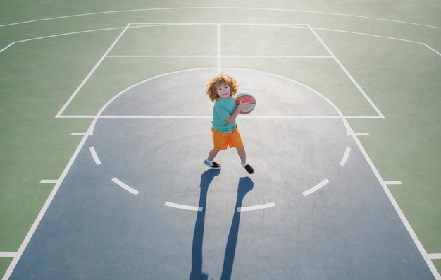 Niño niño preparándose para disparar baloncesto al aire libre en el patio de recreo