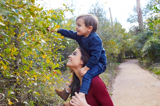 niño niño sentarse sobre los hombros de la madre recogiendo licencia