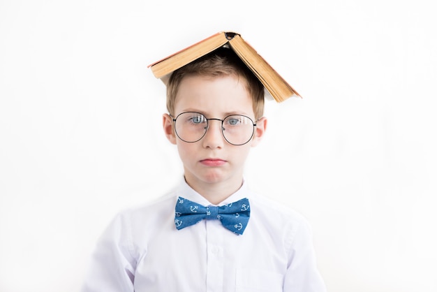 Niño niño serio en vasos bajo techo de libro.