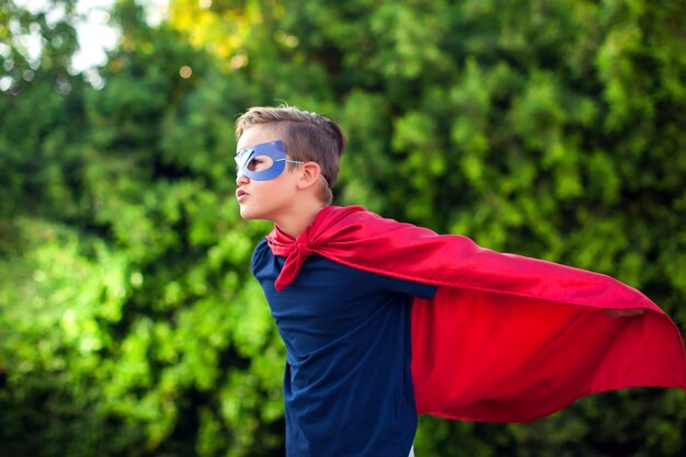 Niño niño superhéroe contra verde al aire libre