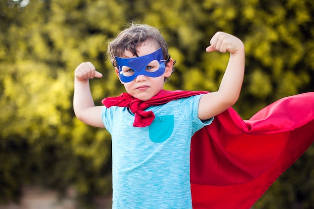 Niño niño superhéroe contra verde al aire libre