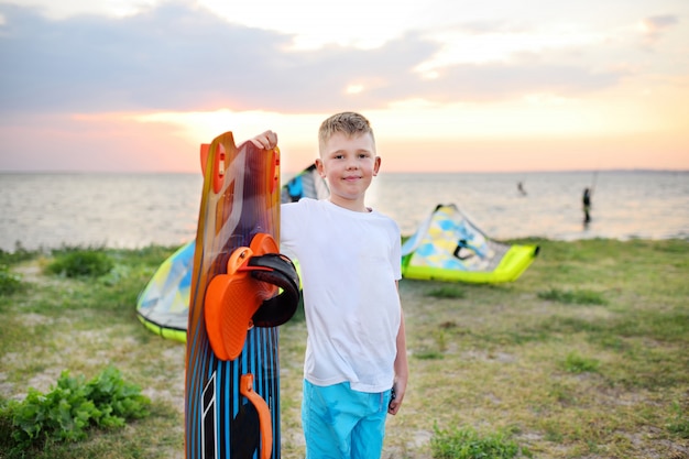 Niño niño con una tabla para nadar o surfear sonriendo en el mar