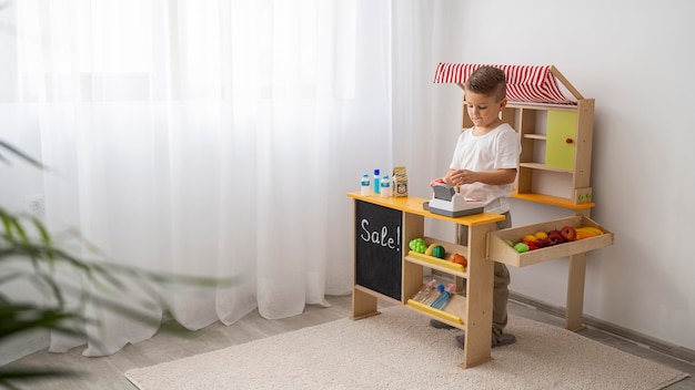 Foto niño no binario jugando en interiores con espacio de copia