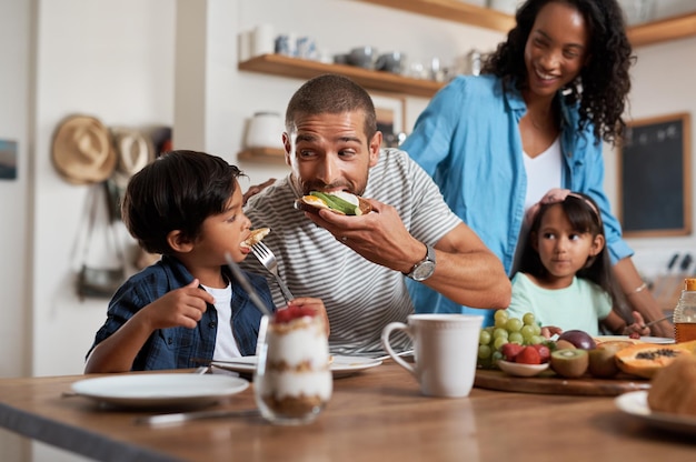 El niño no puede resistirse a un buen desayuno Fotografía de una familia de cuatro personas disfrutando del desayuno juntos en casa