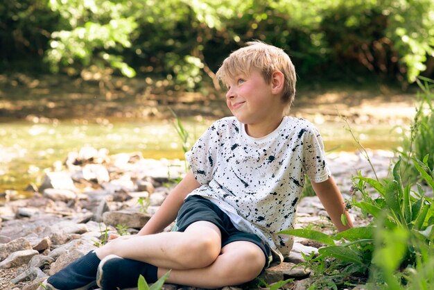 Un niño de nueve años cerca de un pequeño río en verano.