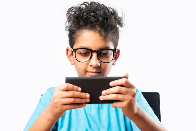 Niño o niño asiático indio que usa el teléfono inteligente para juegos o para la educación