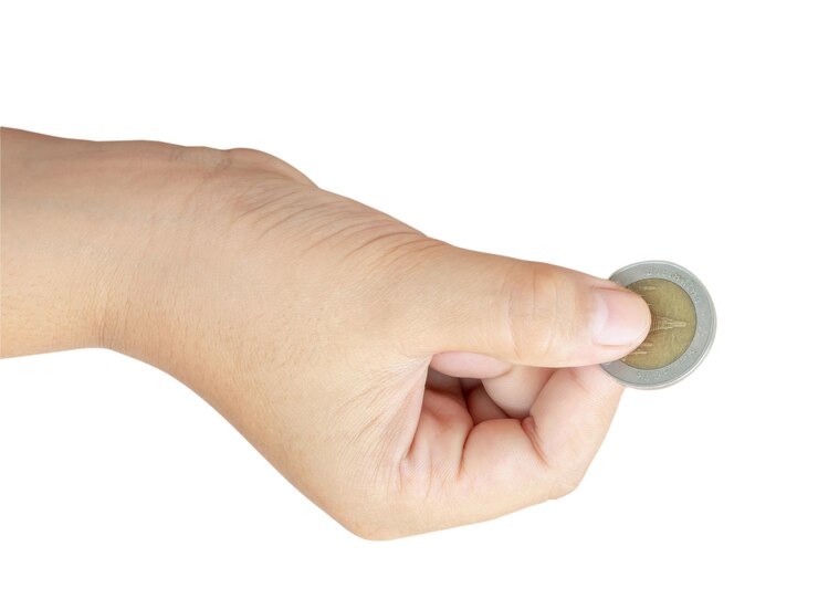 Foto niño o niño con la mano sosteniendo una moneda aislada sobre un fondo blanco con camino de recorte concepto de ahorro