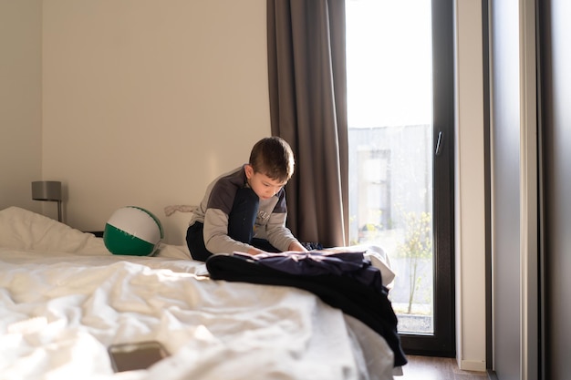 Un niño de ocho años se sienta en un dormitorio en una cama y lee un libro Un niño lindo en pijama leyendo un libro de juguete sentado en la cama Cuentos antes de acostarse