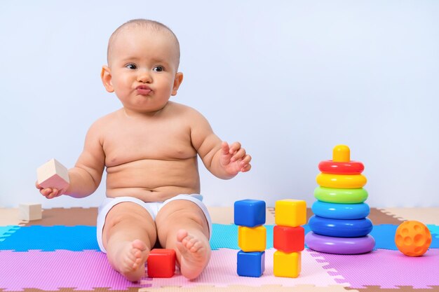 Niño ofendido de 8 a 12 meses, con juguetes en la sala de juegos.