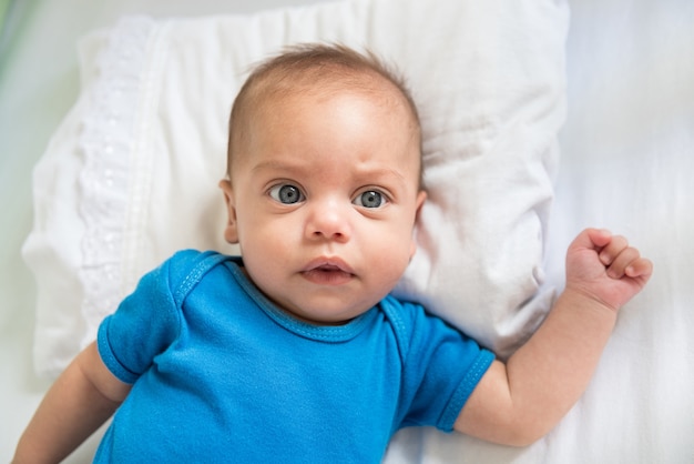 Niño de ojos azules acostado en la cuna